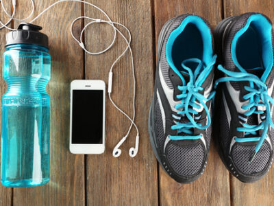 Sneakers and earphones on wooden table, top view