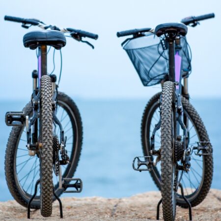 Two bicycles standing on the concrete pier on the blue water background